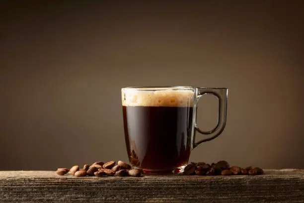 Taza transparente con café lungo y granos de café